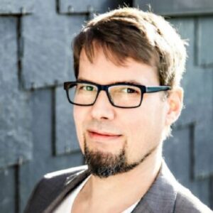 Smiling Christian with dark glasses, brown eyes and a short beard.